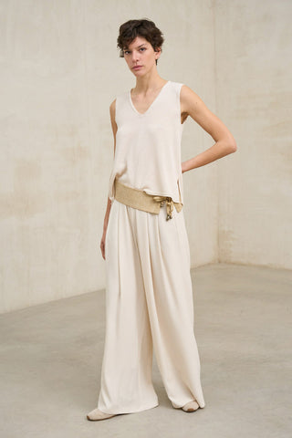 Mujer con look elegante compuesto por top y pantalón amplio monocromático combinado con fajín  en color arena